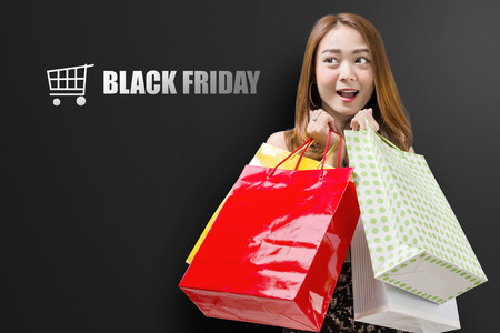 Cheerful asian woman with many shopping bags. Black friday conceptの写真素材