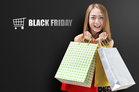 Attractive asian luxury woman holding colored paper bags. Black friday conceptの写真素材
