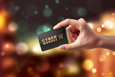 Hands showing black card with text Cyber Monday against blurred lights backgroundの写真素材