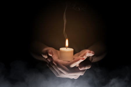 Hands holding candle over dark background. Christian Prayの写真素材