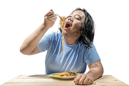 Portrait of asian fat man eating fast food spaghetti isolated over white background. Fat man diet conceptの写真素材