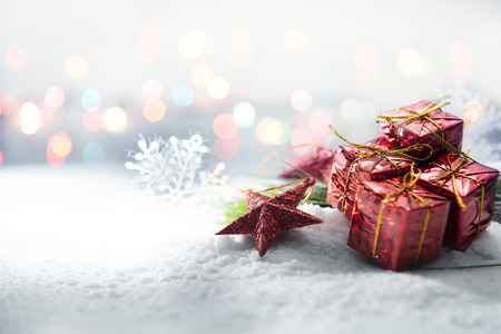 Red star and gift boxes on snow with blurred lights background. Christmas decorationの写真素材