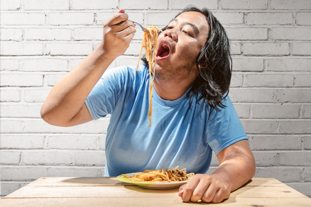 Asian fat man meal the fast food spaghetti at home. Fat man diet conceptの写真素材