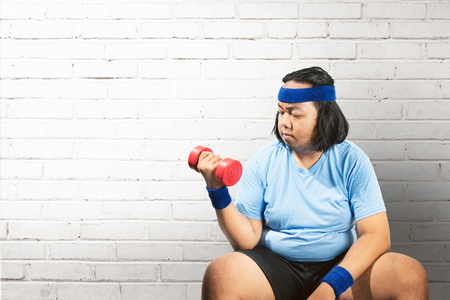 Asian fat man using dumbbell to lose weight at home. Fat man diet conceptの写真素材