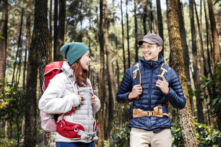 Young asian hikers couple with backpack standing and looking each other in the forestの写真素材