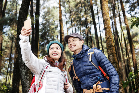 Attractive asian hikers couple taking selfie photo with mobile phone on the forestの写真素材