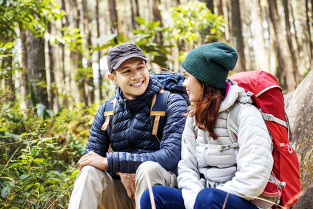 Smiling asian couple hikers with backpack looking at each other on forestの写真素材