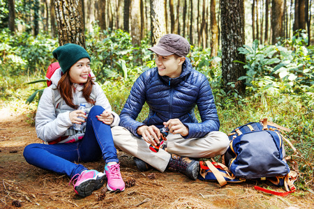 Smiling asian couple hikers take a rest while drink a water on the forestの写真素材