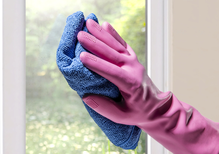 Hands in rubber gloves and micro fiber cloth cleaning window glass at homeの写真素材