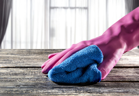 Hands in rubber gloves wiping dust on table with micro fiber cloth at homeの写真素材
