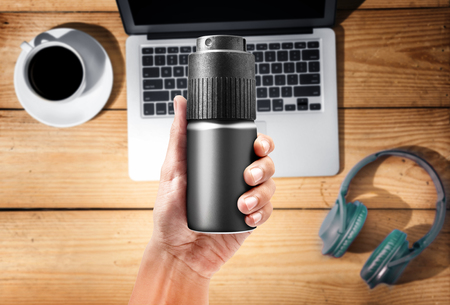Male hands with body spray, notebook, headphones and cup of coffee on the wooden background. Ready...