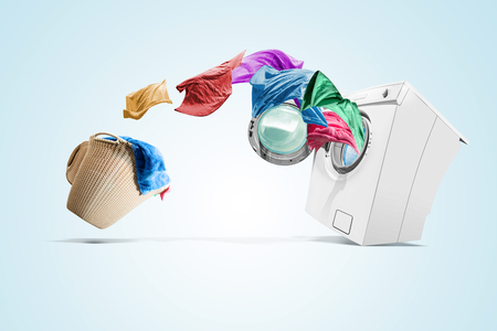 Clothing from laundry basket go into the washing machine over white backgroundの写真素材