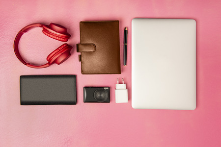 Businessman equipment like laptop, pen, notebook, camera, wallet and headphones for work on pink background. View from aboveの写真素材