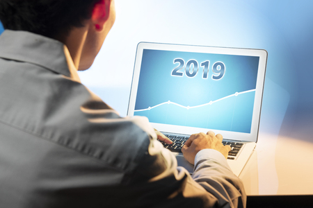 Businessman using laptop with growing financial chart in 2019 on the screen. Business concept. Happy New Year 2019の写真素材