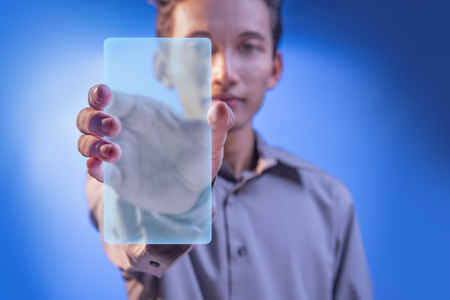 Businessman showing blank virtual screen for copyspace over blue backgroundの写真素材