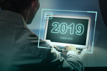 Rear view of businessman with laptop and 2019 on the screen. Business concept. Happy New Year 2019