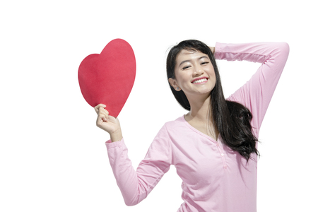 Happy asian woman holding red paper heart posing isolated over white background. Valentines dayの写真素材