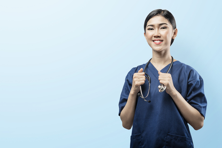 Happy asian doctor woman with stethoscope on her neck over blue backgroundの写真素材