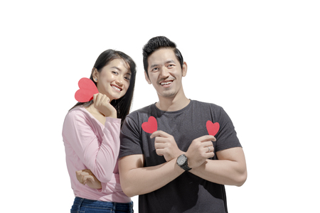 Portrait of asian couple holding red paper hearts posing isolated over white background. Love concept and Valentines dayの写真素材