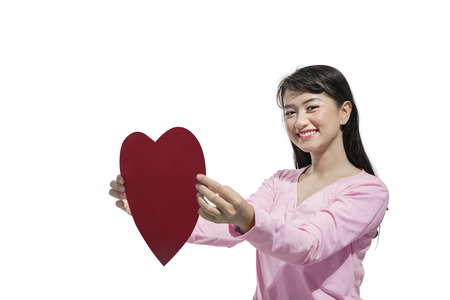 Pretty asian woman holding red heart posing isolated over white background. Valentines dayの写真素材