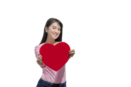 Beautiful asian woman showing red heart shaped standing isolated over white background. Valentines dayの写真素材