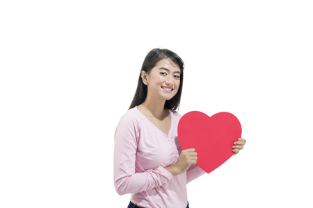Young asian girl holding red hearts standing isolated over white background. Valentines dayの写真素材