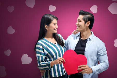 Romantic asian couple in love holding red heart together. Love concept and Valentines dayの写真素材