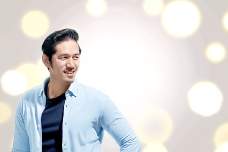 Handsome asian man with blue shirt standing against bokeh lights background. Valentines dayの写真素材
