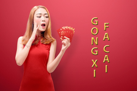 Young chinese woman with cheongsam dress holding red envelopes. Happy Chinese New Yearの写真素材