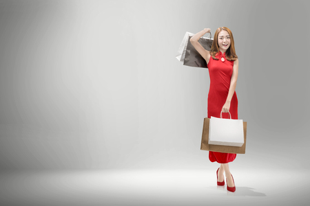 Pretty chinese woman with cheongsam dress carrying shopping bags. Happy Chinese New Yearの写真素材