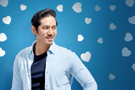 Happy asian man in blue casual clothes standing over valentines background. Valentines dayの写真素材