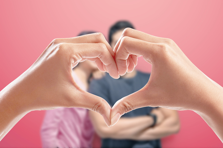 Human hands making heart shape with happy couple on the background. Love concept and Valentines dayの写真素材