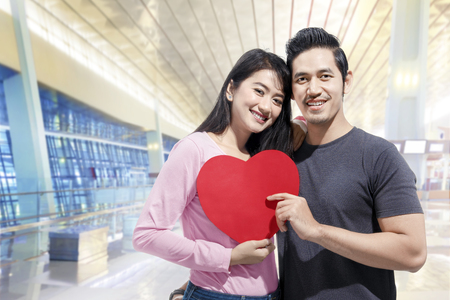 Romantic asian couple in love standing together and holding red heart shape. Love concept and Valentines dayの写真素材
