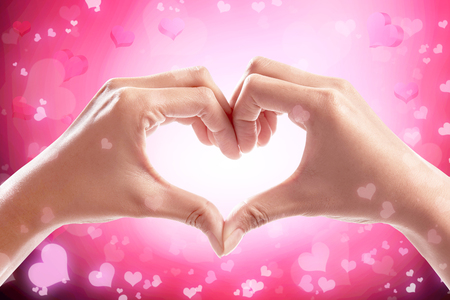 Human hands making heart shape over pink background. Valentines dayの写真素材