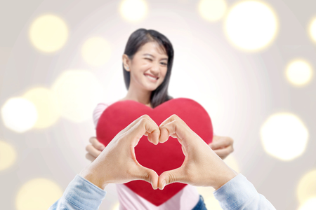 Man hands with heart shape and asian woman standing while holding heart red paper. Valentines dayの写真素材