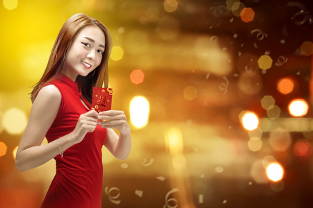 Smiling chinese woman in cheongsam dress holding red envelopes. Happy Chinese New Yearの写真素材