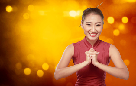 Beautiful chinese woman with cheongsam dress and gesture of congratulation. Happy Chinese New Yearの写真素材