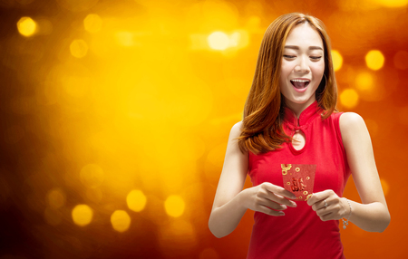 Cheerful chinese woman in traditional dress holding red envelopes. Happy Chinese New Yearの写真素材