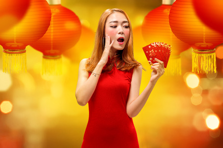Excited chinese woman in traditional dress holding angpao. Happy Chinese New Yearの写真素材