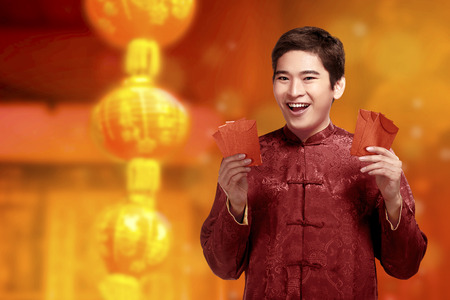 Handsome chinese man with cheongsam clothes showing red envelopes on his hands. Happy Chinese New Yearの写真素材