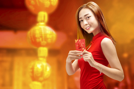 Young chinese woman in cheongsam dress holding angpao. Happy Chinese New Yearの写真素材