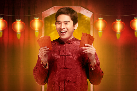 Handsome chinese man in traditional clothes holding angpao. Happy Chinese New Yearの写真素材
