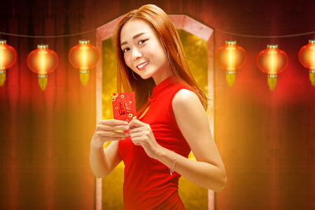 Smiling chinese woman with traditional dress holding red envelopes. Happy Chinese New Yearの写真素材