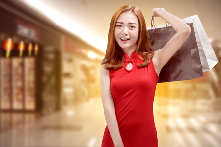 Pretty chinese woman in traditional dress carrying shopping bags. Happy Chinese New Yearの写真素材