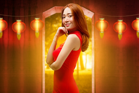 Happy chinese woman with traditional clothes posing against hanging lanterns on the background. Happy Chinese New Yearの写真素材