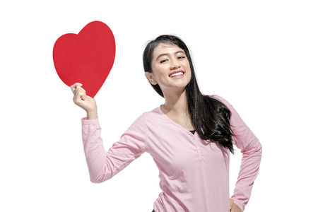 Portrait of asian woman holding red heart on her hands posing isolated over white background. Valentines dayの写真素材