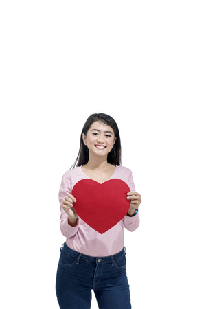 Young asian woman holding red paper hearts posing isolated over white background. Valentines dayの写真素材