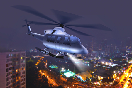 Helicopter flying over the city at nightの写真素材