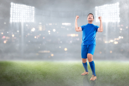 Happy asian soccer player man celebrate the victory on the stadiumの写真素材