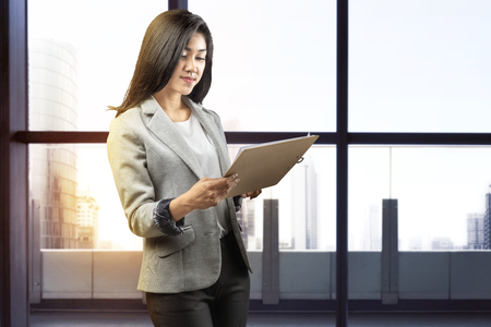Pretty asian businesswoman with clipboard on the officeの写真素材